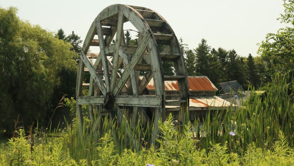 A water wheel with buildings in background