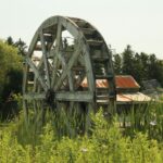 A water wheel with buildings in background