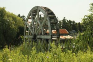 A water wheel with buildings in background